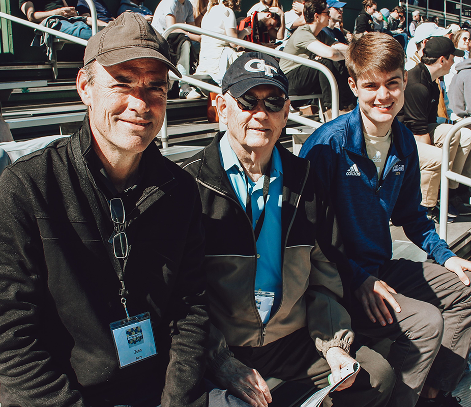 Father, grandfather, and grandson enjoying a baseball game.