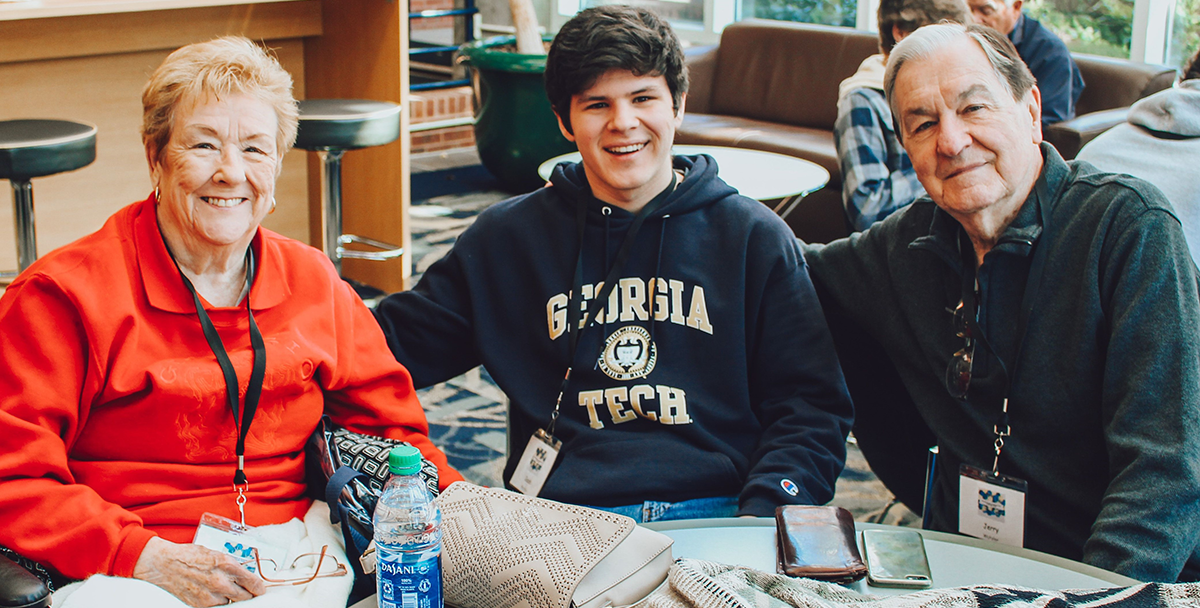 Grandmother, grandson wearing a GT sweatshirt and grandfather smiling at the camera.