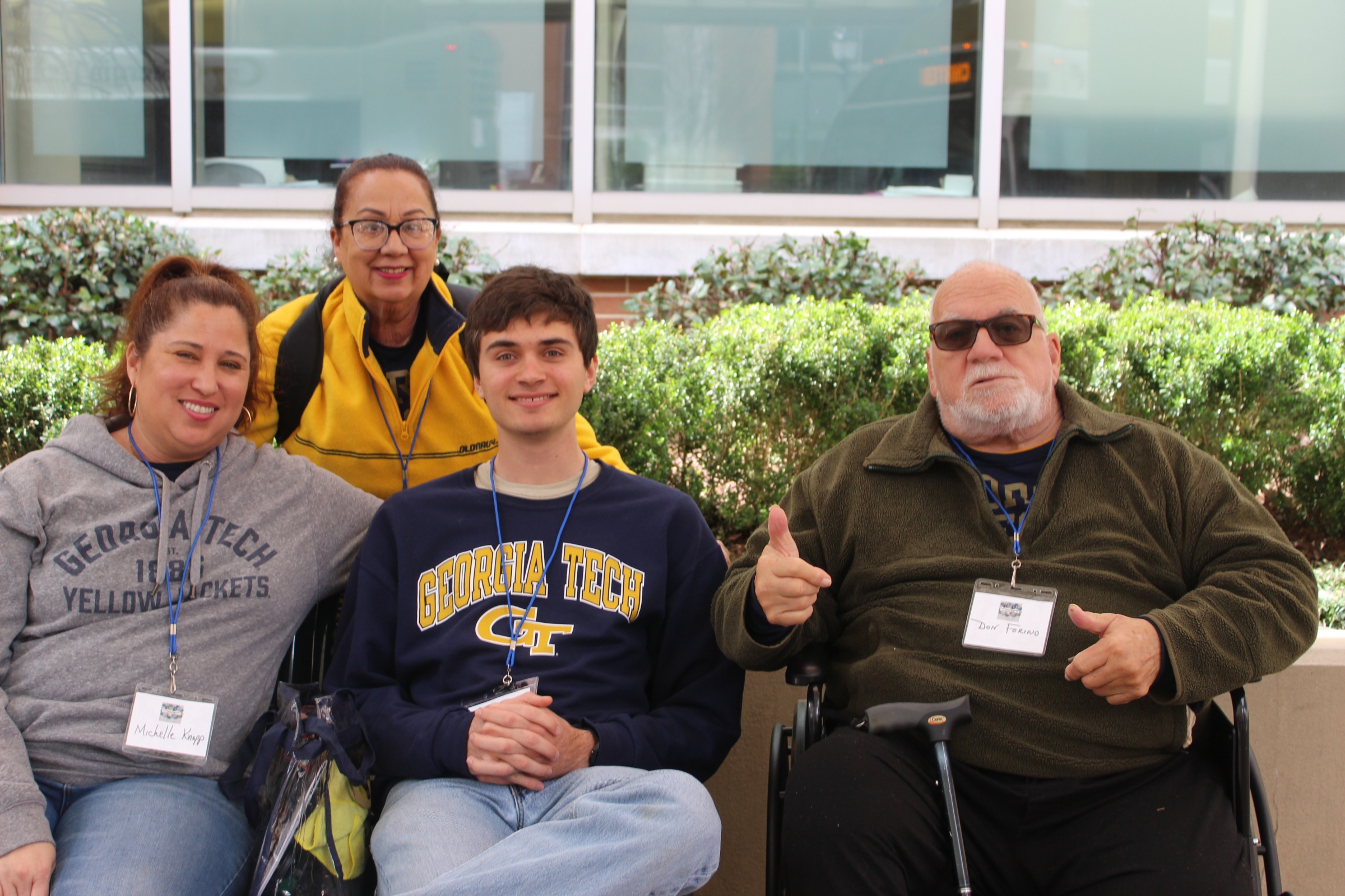 A young man wearing a Georgia Tech sweatshirt is surrounded by parents and grandparents, some standing, some sitting